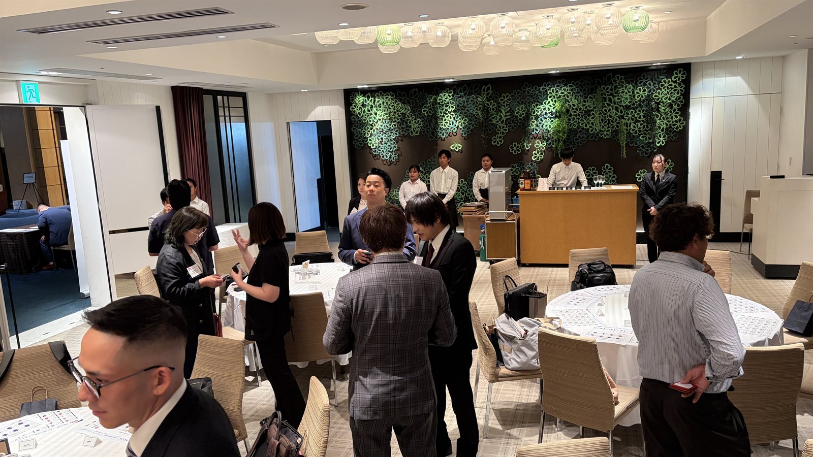 Guests networking at the NEXIA founding celebration, exchanging business cards and talking in small groups